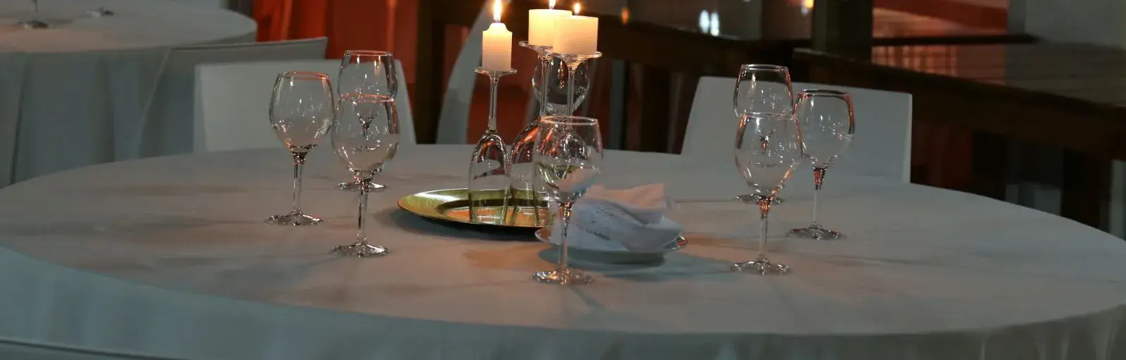 Mesa puesta de noche, con mantel blanco, copas y un candelabro