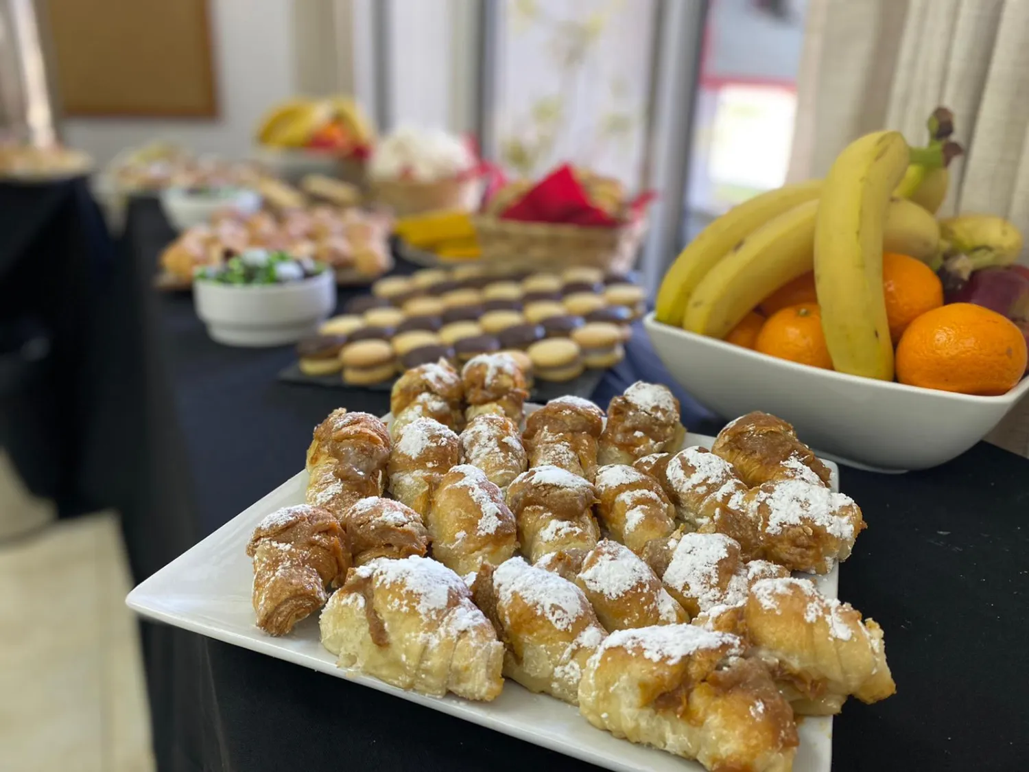 Mesa de coffee break con cañoncitos, alfajores y fruta